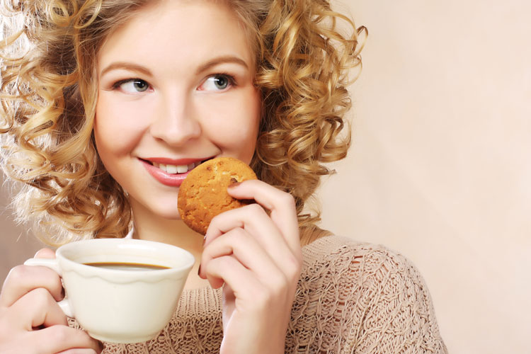 Smiling young woman with tea and cookie