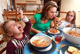Preschooler making a mess sharing spaghetti with family 