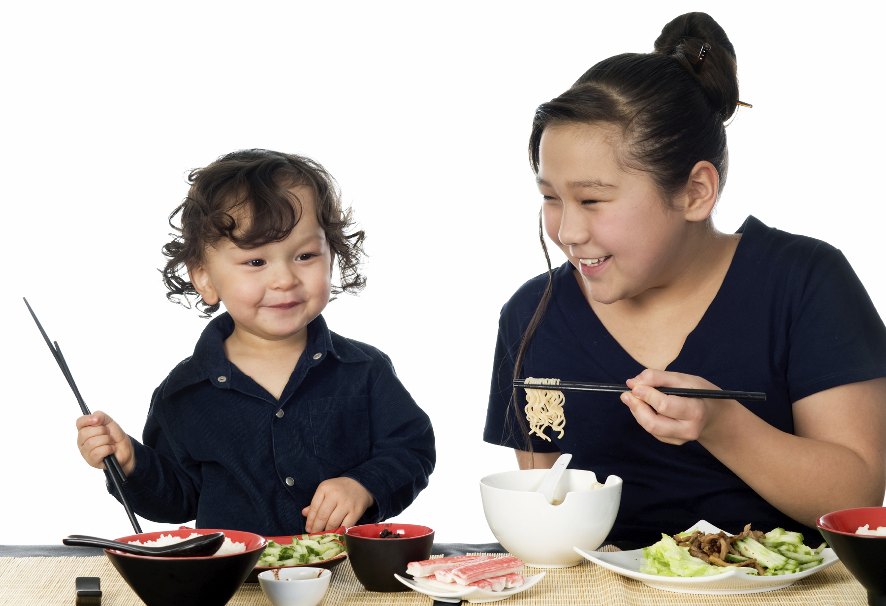 Preschool boy and mother enjoy eating a meal with chopsticks