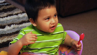Toddler at table talking and squirming while he eats Toddler at table talking and squirming while he eats