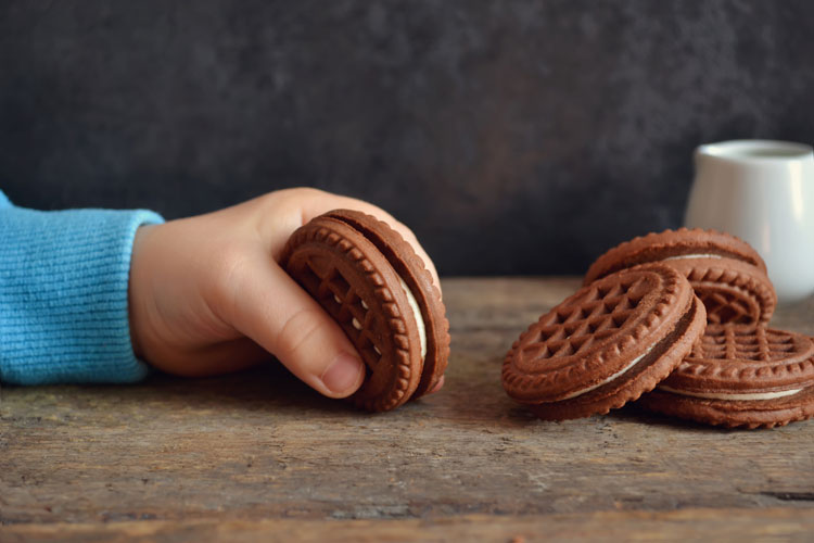 Toddler hand with cookies and milk