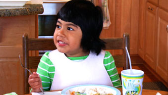 Preschool girl smiling and talking at family meal 