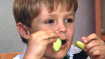 Preschooler happily feeding himself with his fingers at family meal